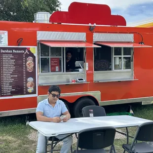 a man sitting at a table in front of a food truck