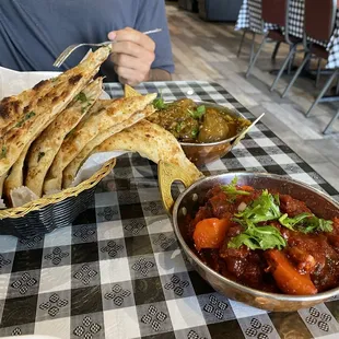 Garlic naan, curried goat at back. Forgot name of food in foreground