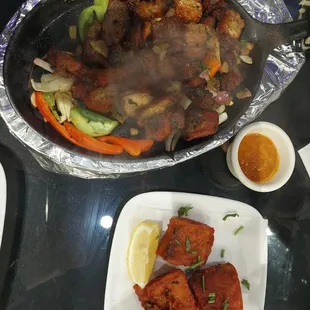 Pork sekwa on sizzling skillet and fried tilapia with lemon