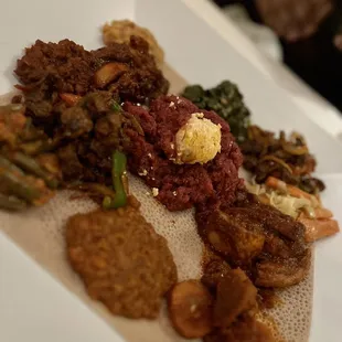 Kitfo - Steak Tartare- middle, veggie sample on the corners, Lamb Tibs, Chicken Infillay