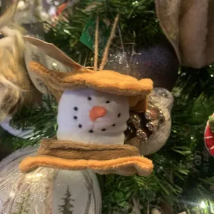 a snowman ornament hanging from a christmas tree