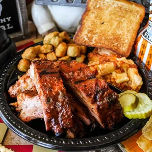 a plate of ribs, potatoes, and chips