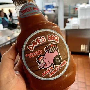 a hand holding a bottle of barbecue sauce