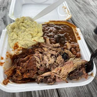 pulled pork, beans, and mashed potatoes in a styrofoam container