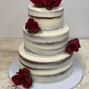 a three tiered cake with red roses on top