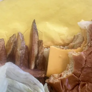 a half eaten sandwich with lettuce and a wedge of cheese