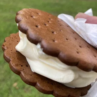 a hand holding a sandwich with ice cream