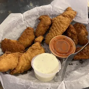 a basket of fried chicken with dipping sauce