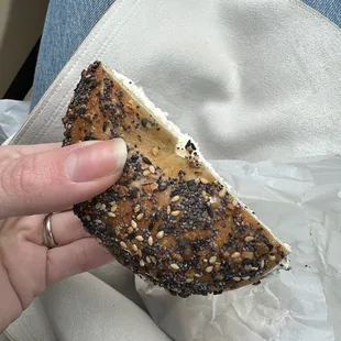a hand holding a bagel sandwich