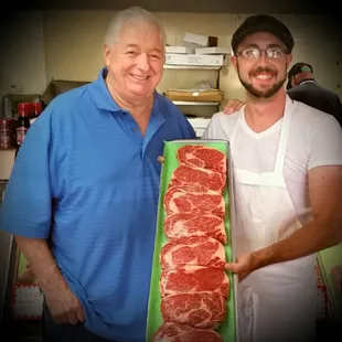 a man and a man holding a large slab of meat