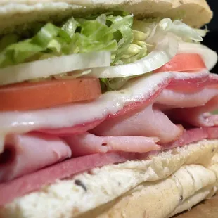 a sandwich with ham, lettuce, tomato, and cheese