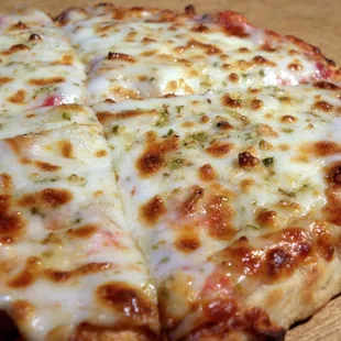 a cheesy pizza on a cutting board