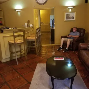 Living area with bar, mini kitchen, and flat screen TV in Fisher Suite.