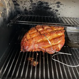 a large piece of meat cooking on a grill