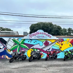 motorcycles parked in front of a colorful mural