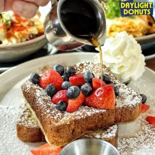 a plate of french toast with strawberries and blueberries