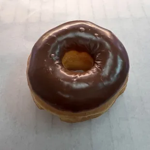 a chocolate frosted donut on a white surface