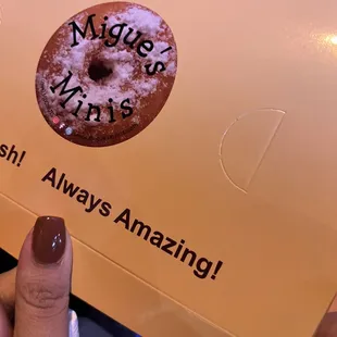 a hand holding a box of doughnuts