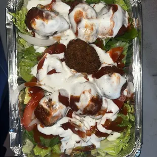 Falafel platter with lettuce, topped with garlic and spicy sauces