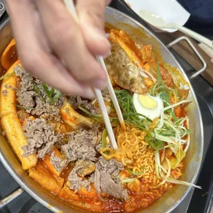 a person holding chopsticks over a bowl of food