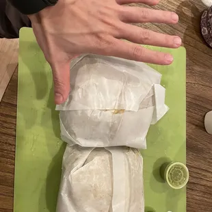 a person's hand reaching for a burrito