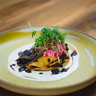 Taquitos Fritos - one with potato, one with pork, served on top of a lime crema and dotted with salsa negra.