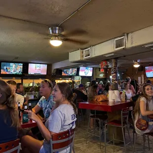 people sitting at tables watching tvs