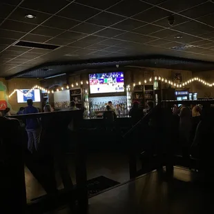 people sitting at a bar watching televisions