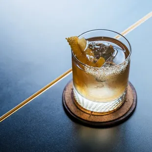 a drink in a glass on a wooden coaster