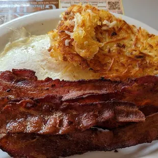 Smoked bacon resting on crispy hash brown atop over medium eggs.