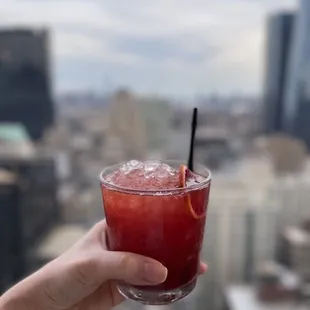 a hand holding a cocktail with a straw