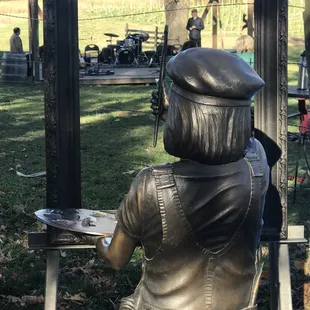 a bronze statue of a boy painting