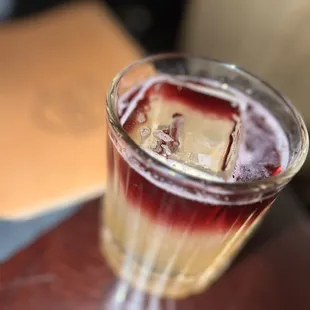 a glass of liquid with ice cubes