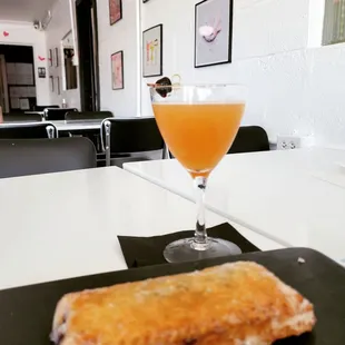 a glass of orange juice and a piece of bread
