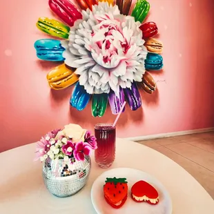 a vase of macarons and a plate of strawberries