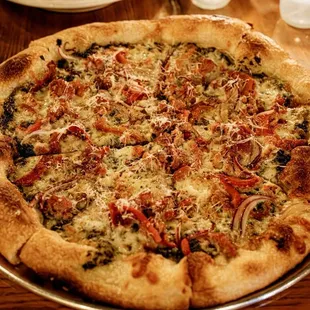 Pizza with fennel sausage, roasted red peppers, onion, basil pesto, mozzarella, grana padano