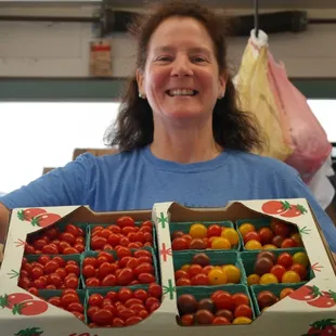 a woman holding a box of tomatoes