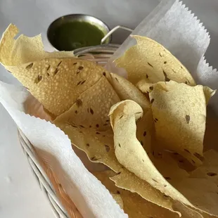 a basket of tortilla chips and a small bowl of guacamole