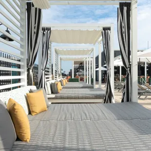 a view of a covered patio with lounge chairs and umbrellas