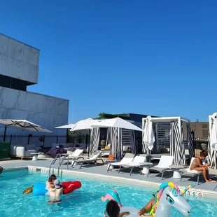 people in a pool with inflatable floats