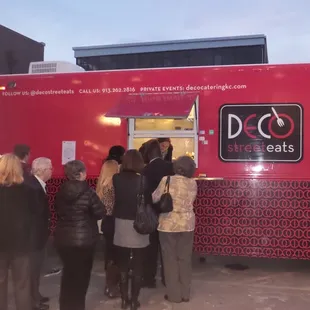 a group of people standing in front of a food truck