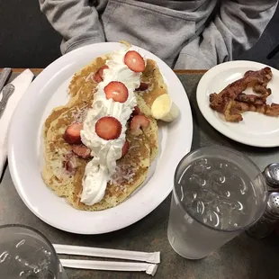 a plate of pancakes with strawberries and bacon