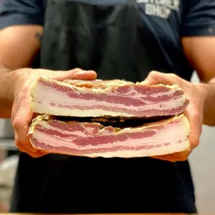 a man holding two slices of bacon