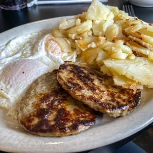 Two eggs over medium with hash browns and sausage patties.