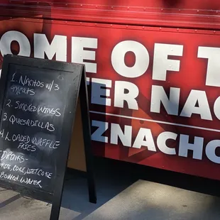 a chalkboard sign in front of a food truck