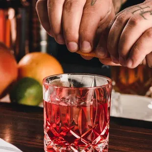 a bartender squeezing a cocktail into a glass