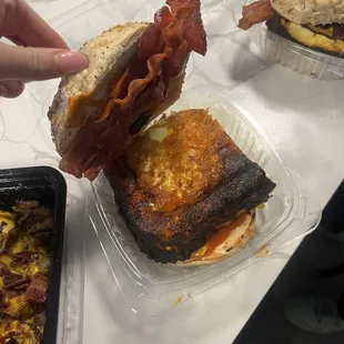 a person grabbing a sandwich from a plastic container