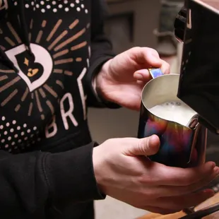 a person pouring milk into a mug