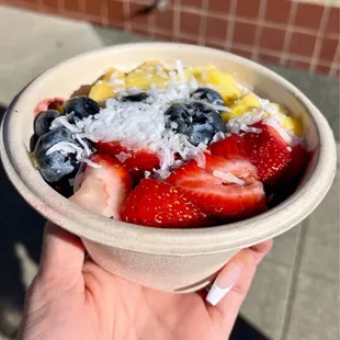 a hand holding a bowl of fruit