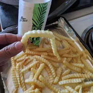 a hand holding a piece of french fries